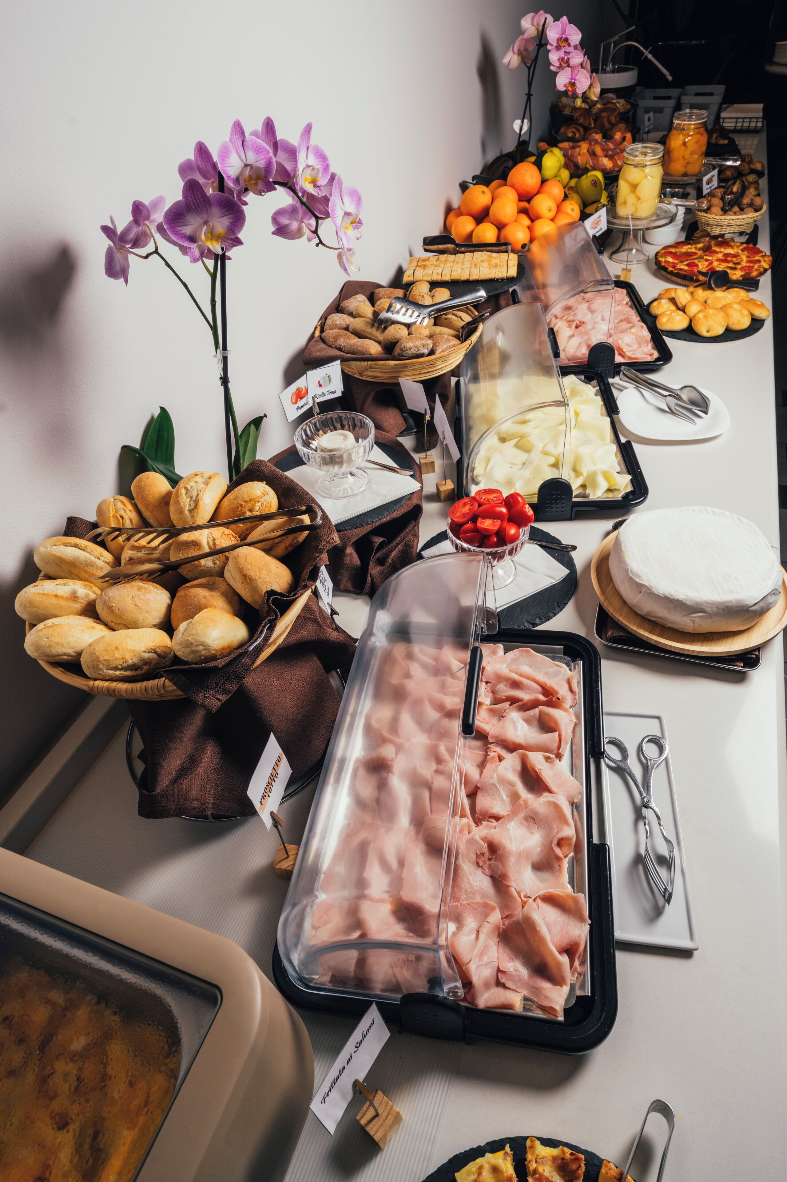 Un bufé con distintos alimentos, incluyendo pan, carnes, frutas y un pastel.