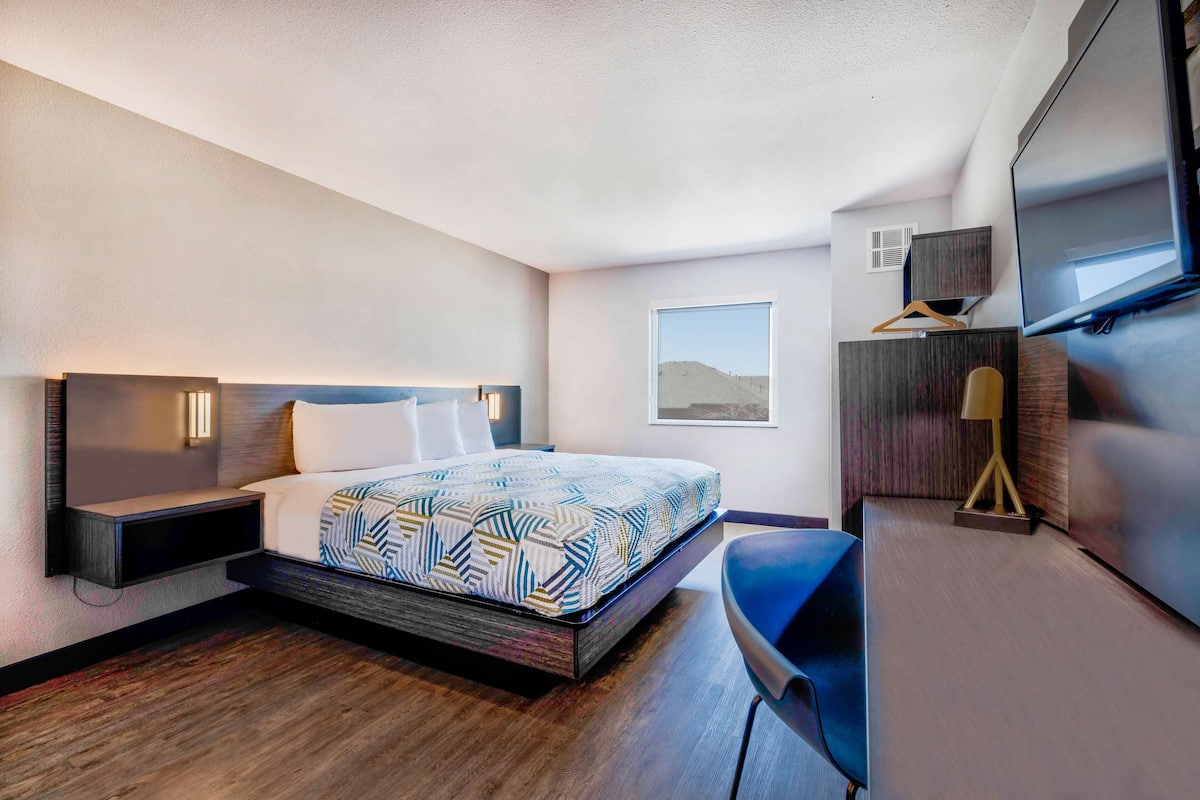 A modern hotel room with a large bed, a desk, and a TV.