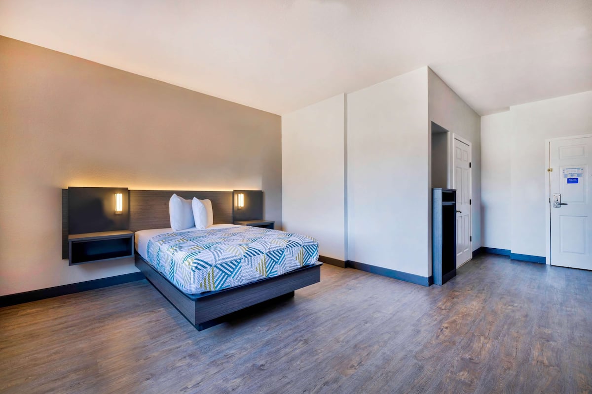 A modern hotel room with a bed, bedside tables, and a wardrobe.