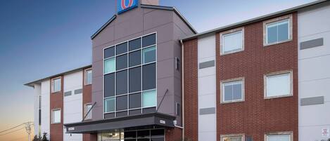 A modern hotel with a prominent '6' sign, large windows, and a brick facade.