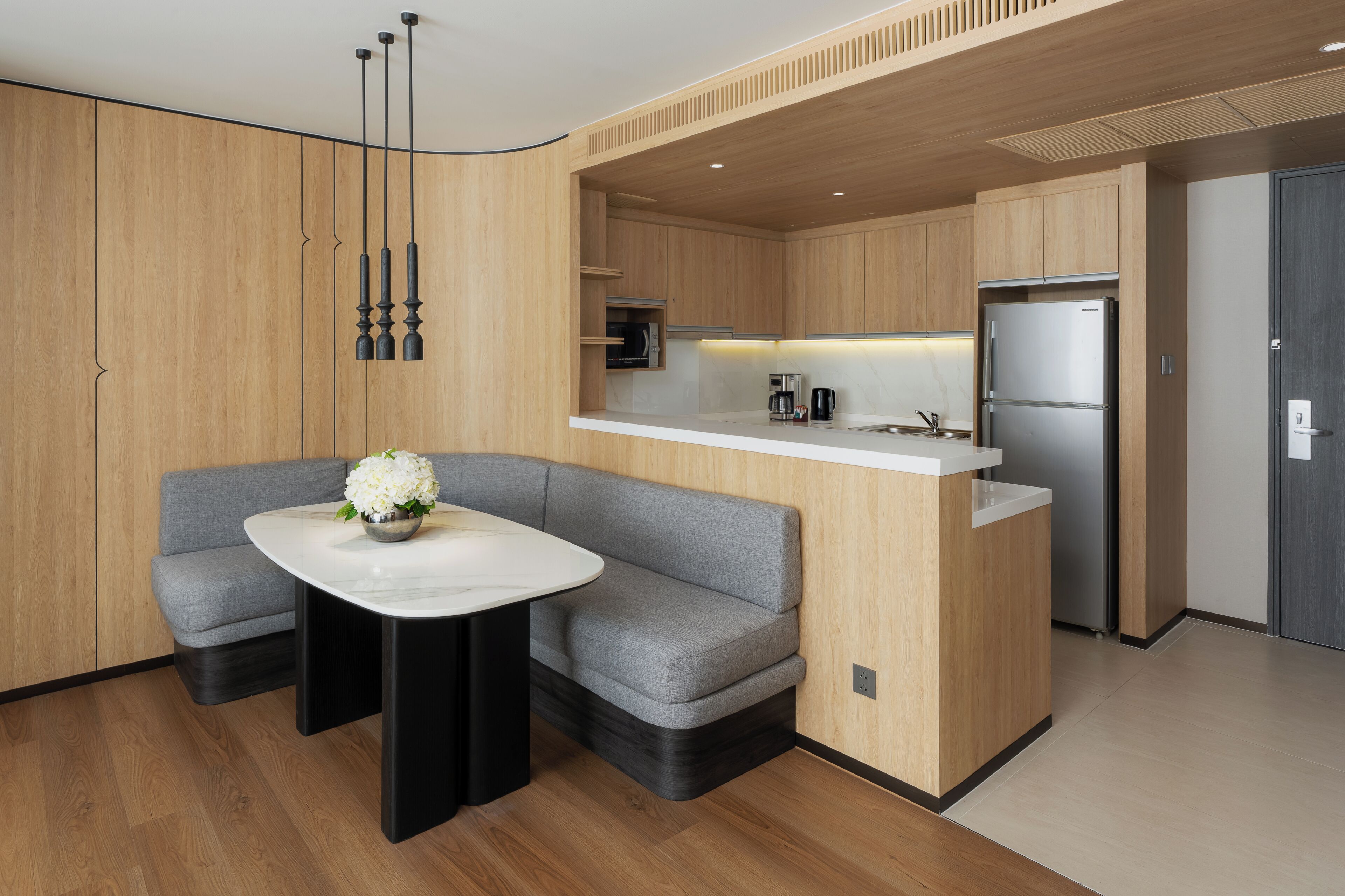 A modern kitchen with a built-in island, stainless steel appliances, and a grey sofa with a white vase.