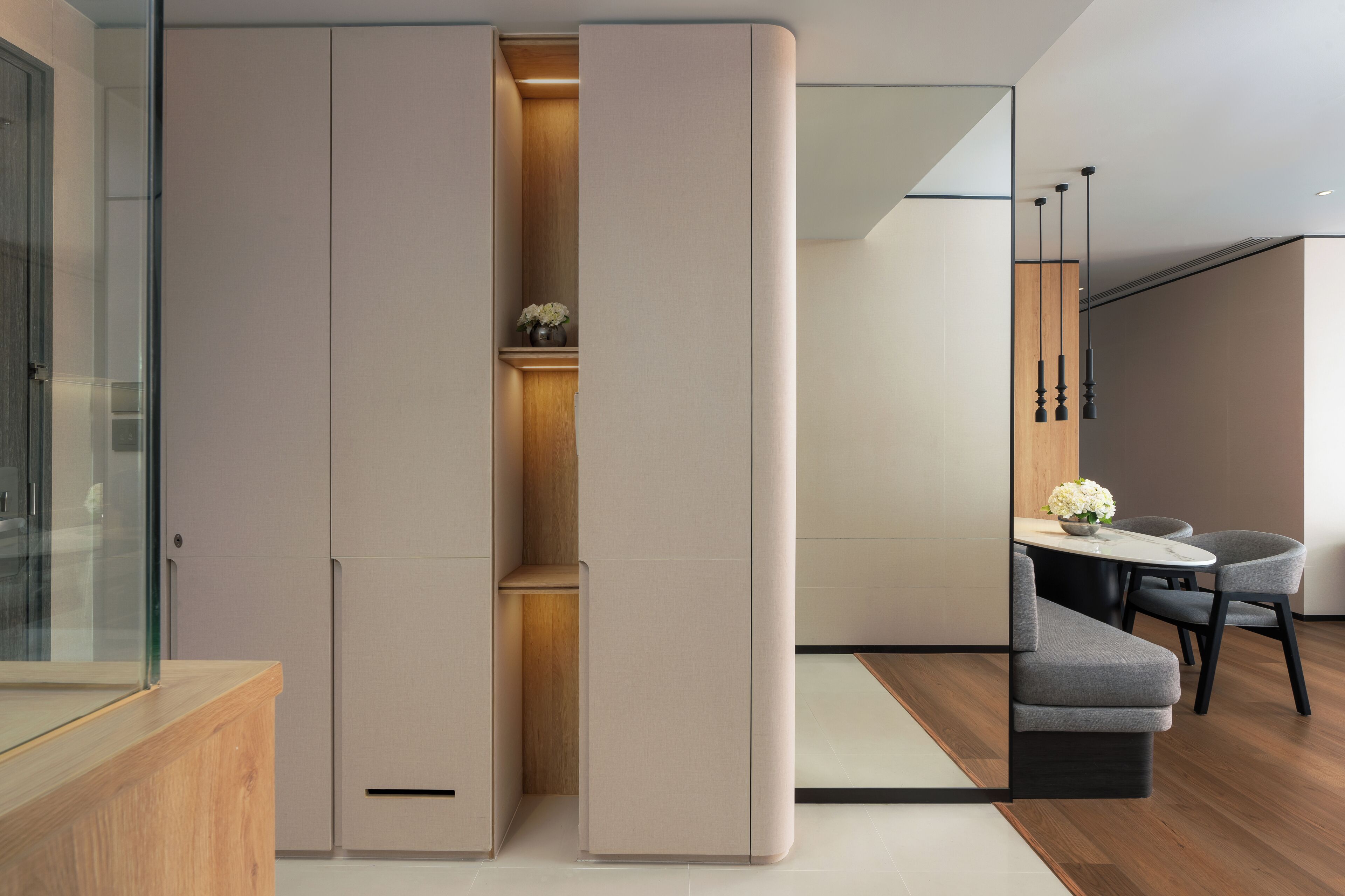 Un interior moderno con armario corredero, un mueble de madera, una zona de comedor con mesa y sillas, y una lámpara colgante.