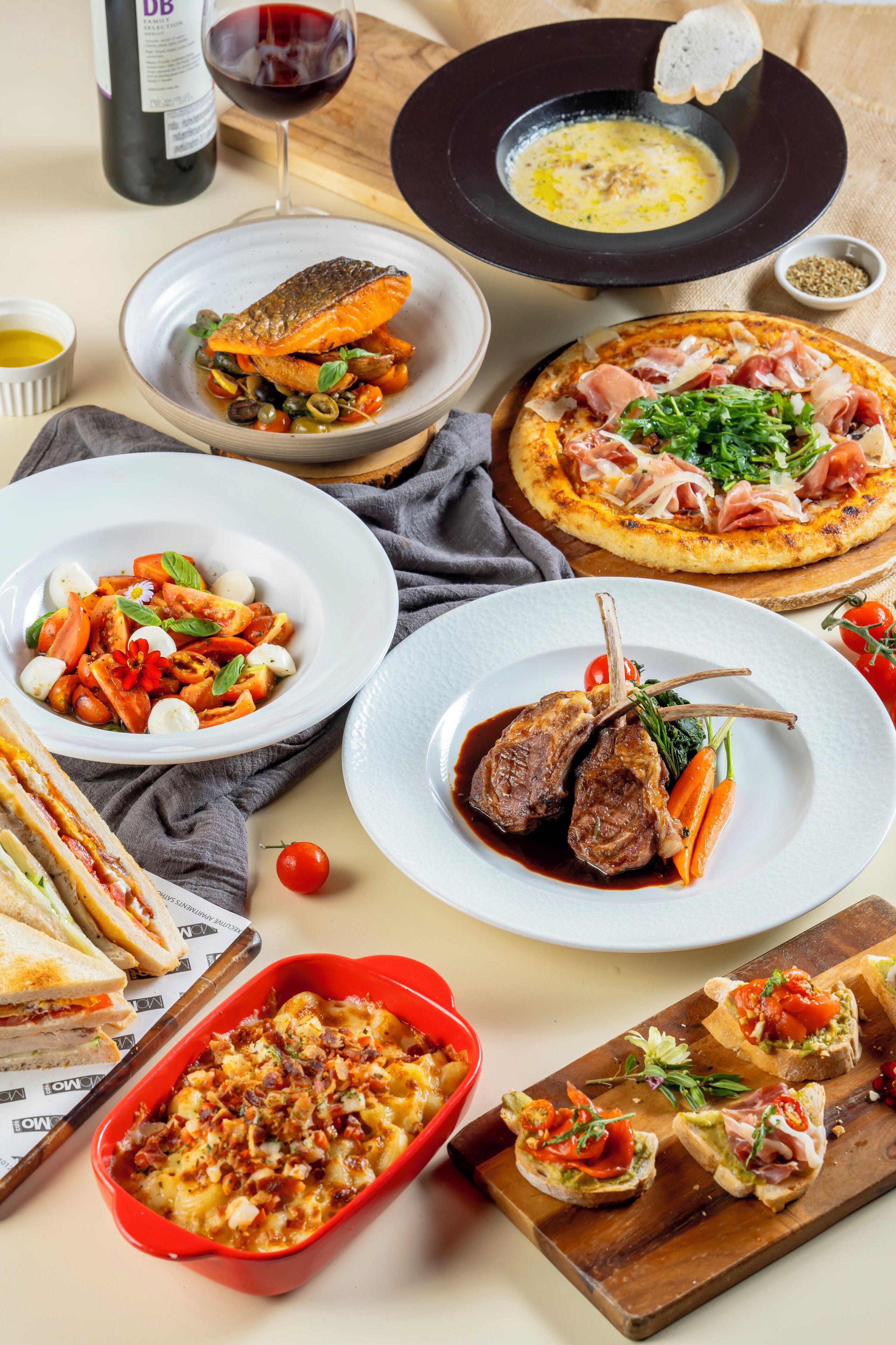 A variety of dishes including a fish dish, a pizza, a meat dish, and a salad.