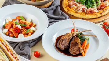 A variety of dishes including a fish dish, a pizza, a meat dish, and a salad.