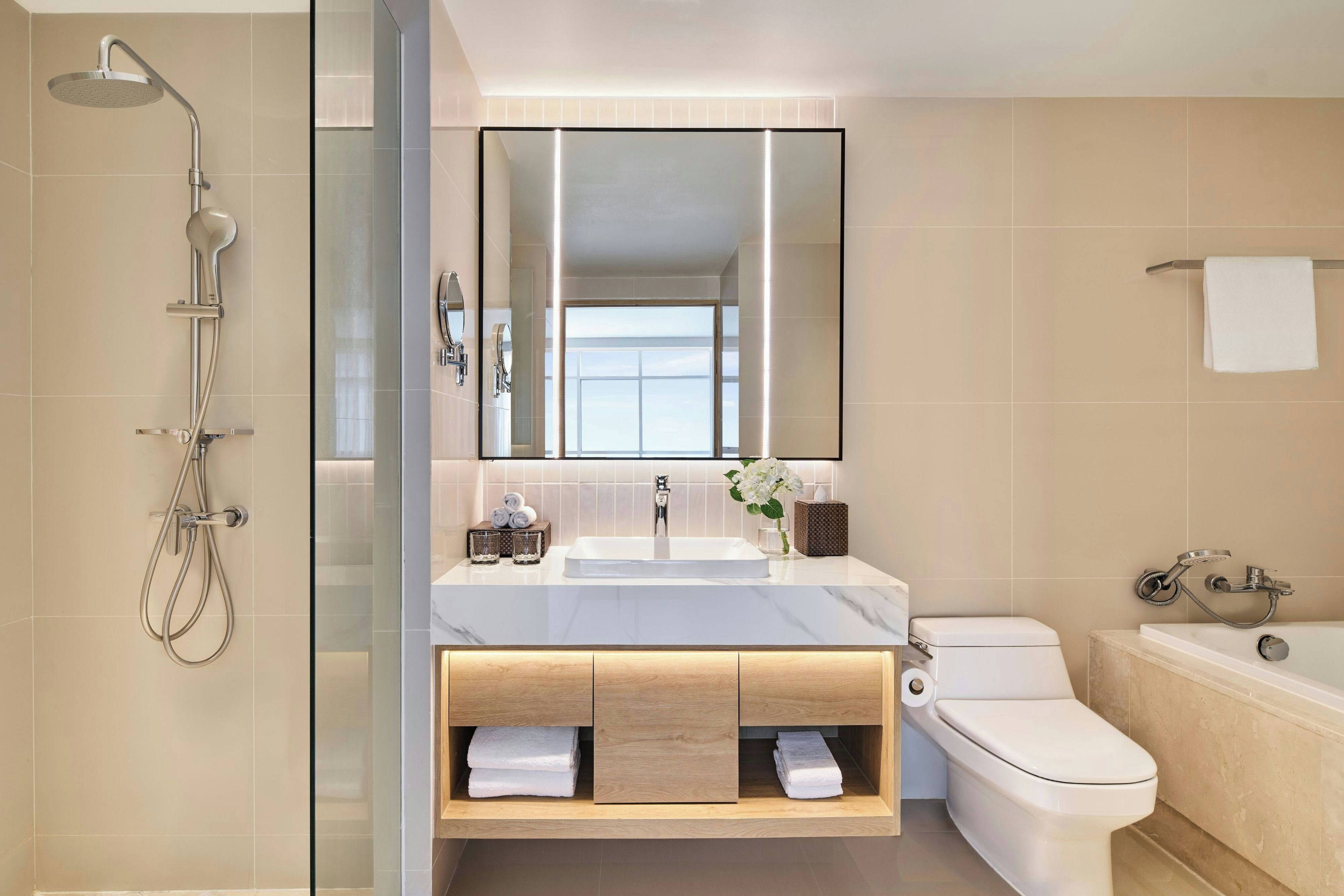 A modern bathroom with a glass-enclosed shower, a large mirror, a white sink, and a toilet.