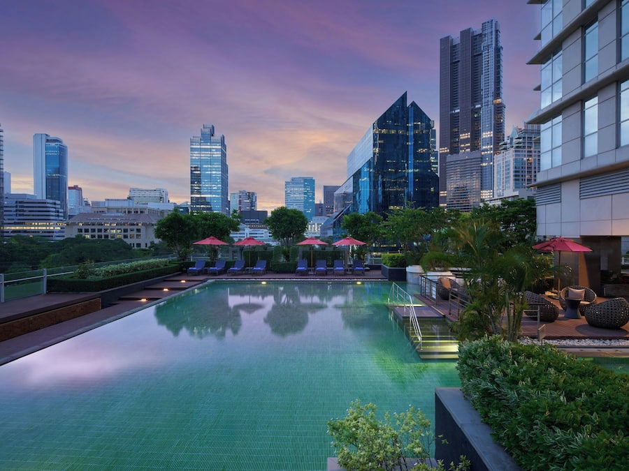 Una piscina infinita en la azotea con el horizonte de la ciudad al fondo.