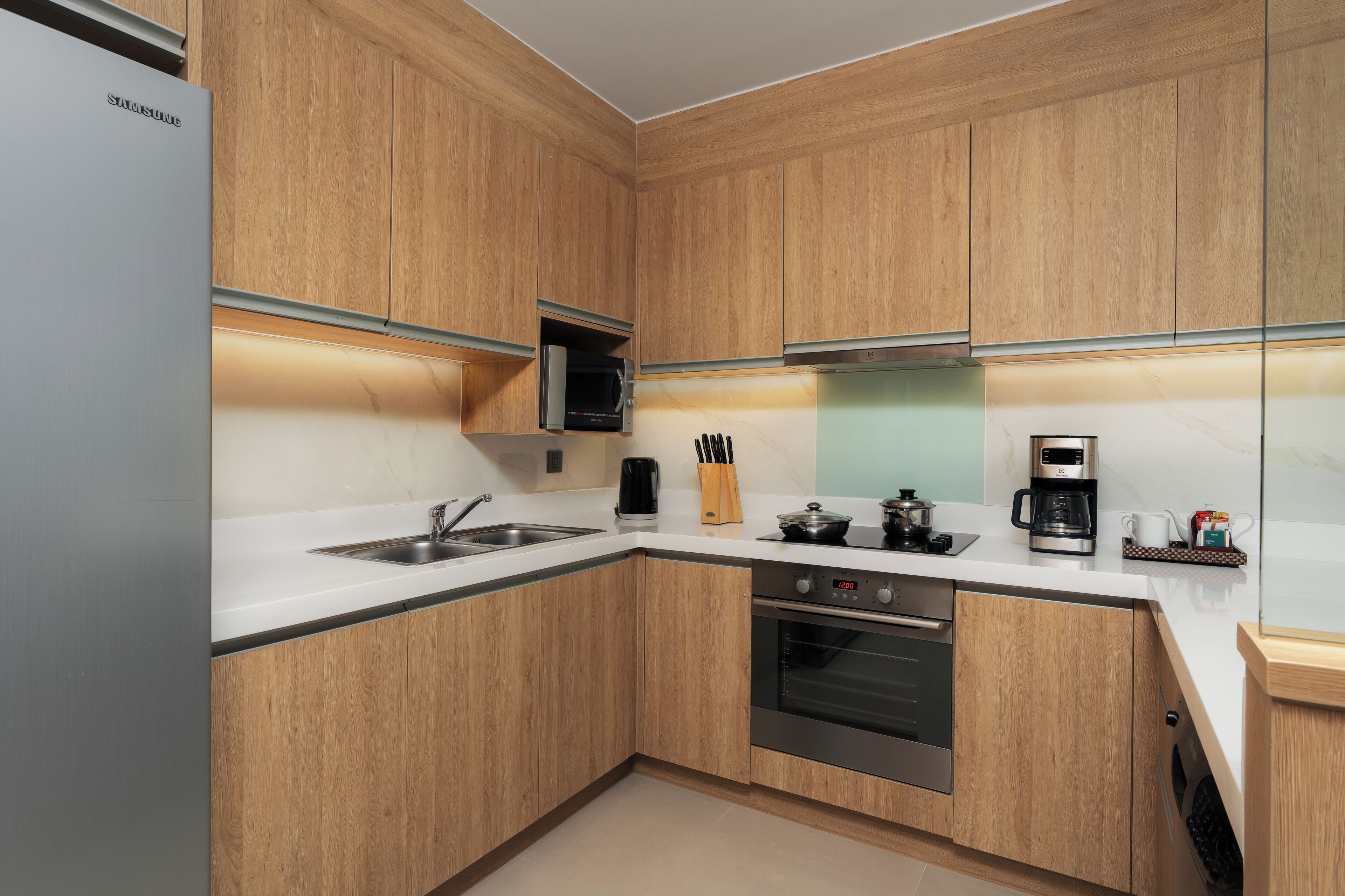 A modern kitchen with wooden cabinets, stainless steel appliances, and a built-in microwave.