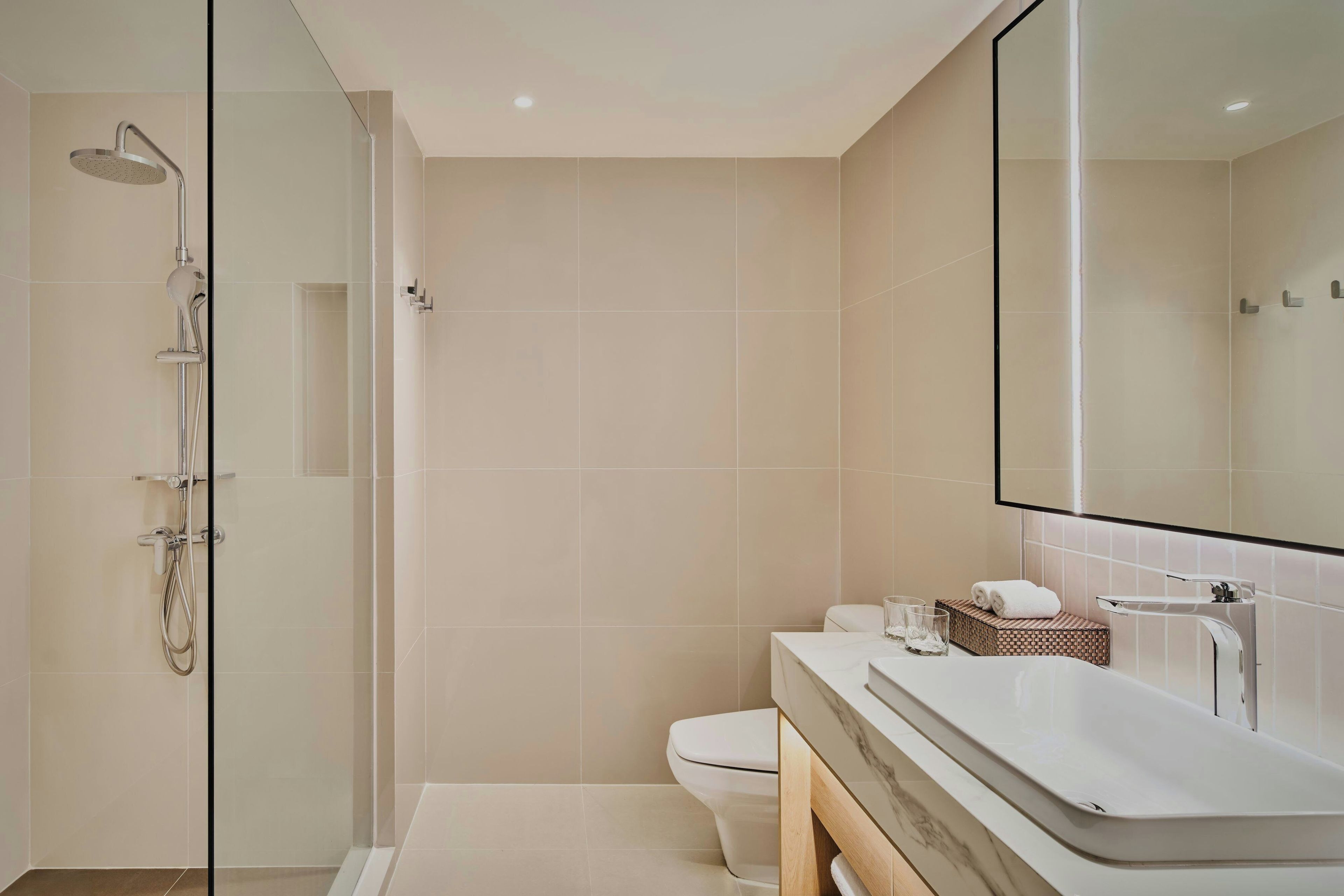 A modern bathroom with a glass-enclosed shower, a white toilet, and a vanity with a mirror.