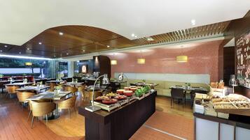 Un restaurante moderno con un bufé central, varias zonas de estar y una pared de ladrillo con un diseño decorativo.