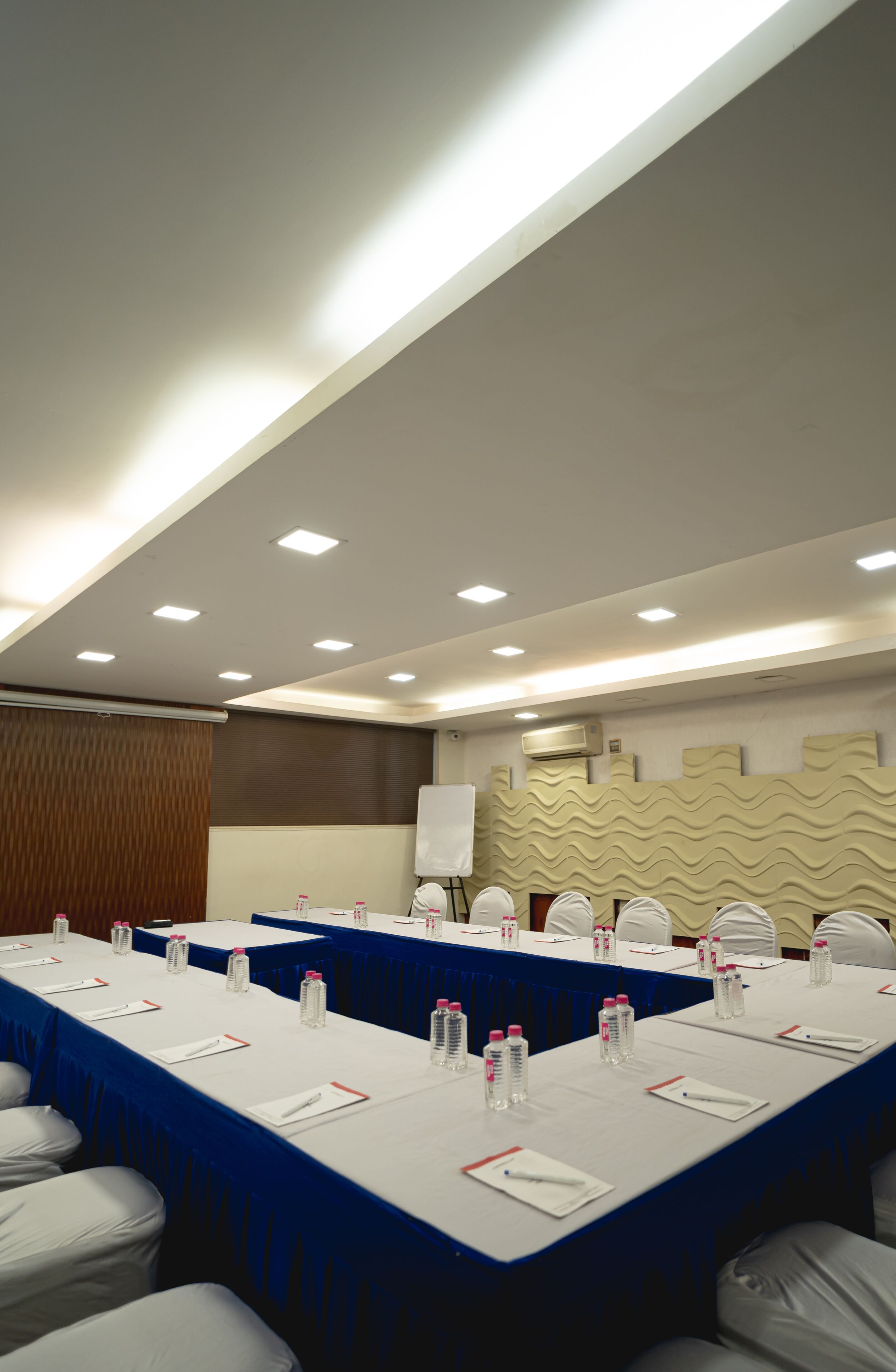 A conference room with a long table, chairs, water bottles, and a whiteboard.