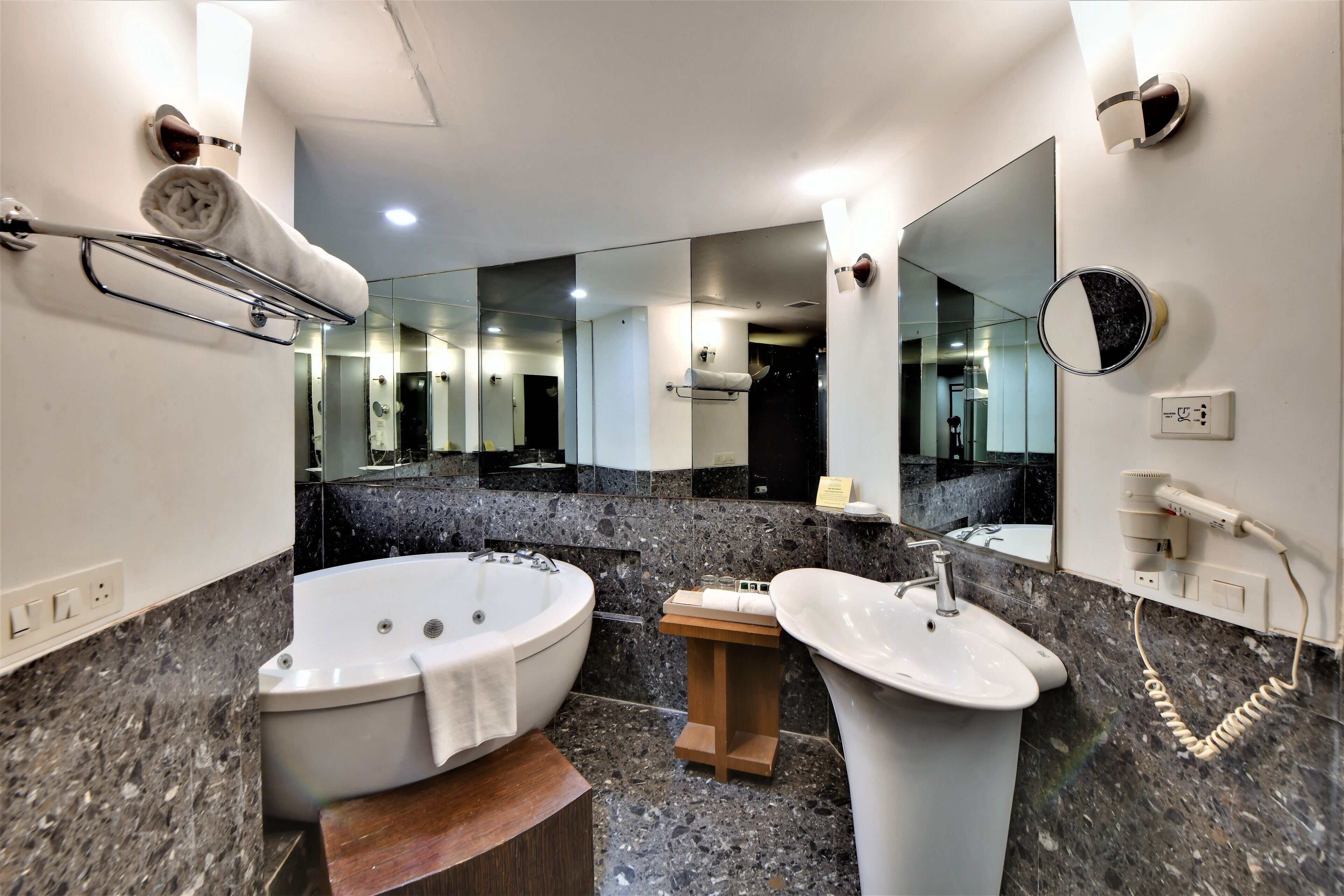Ein modernes Badezimmer mit einer großen Badewanne, einem Waschbecken, einem Spiegel und einem Handtuchhalter.