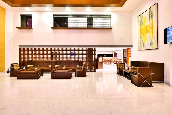 A spacious lobby with a high ceiling, modern furniture, and a large abstract painting.
