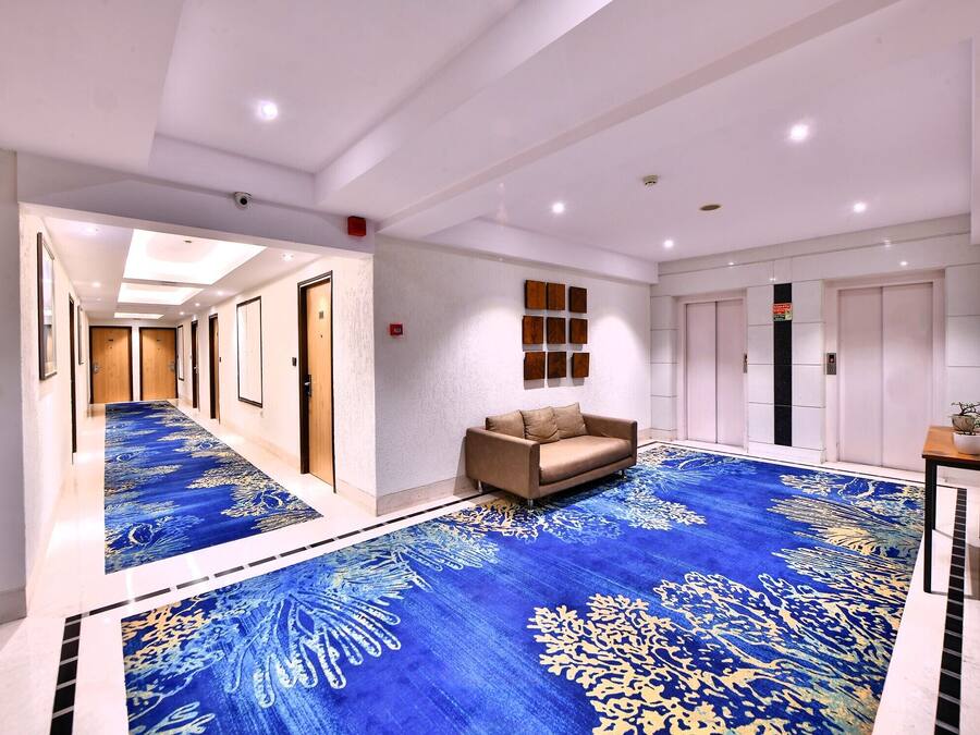 A hotel lobby with a blue carpet, a sofa, and a small table with a plant.