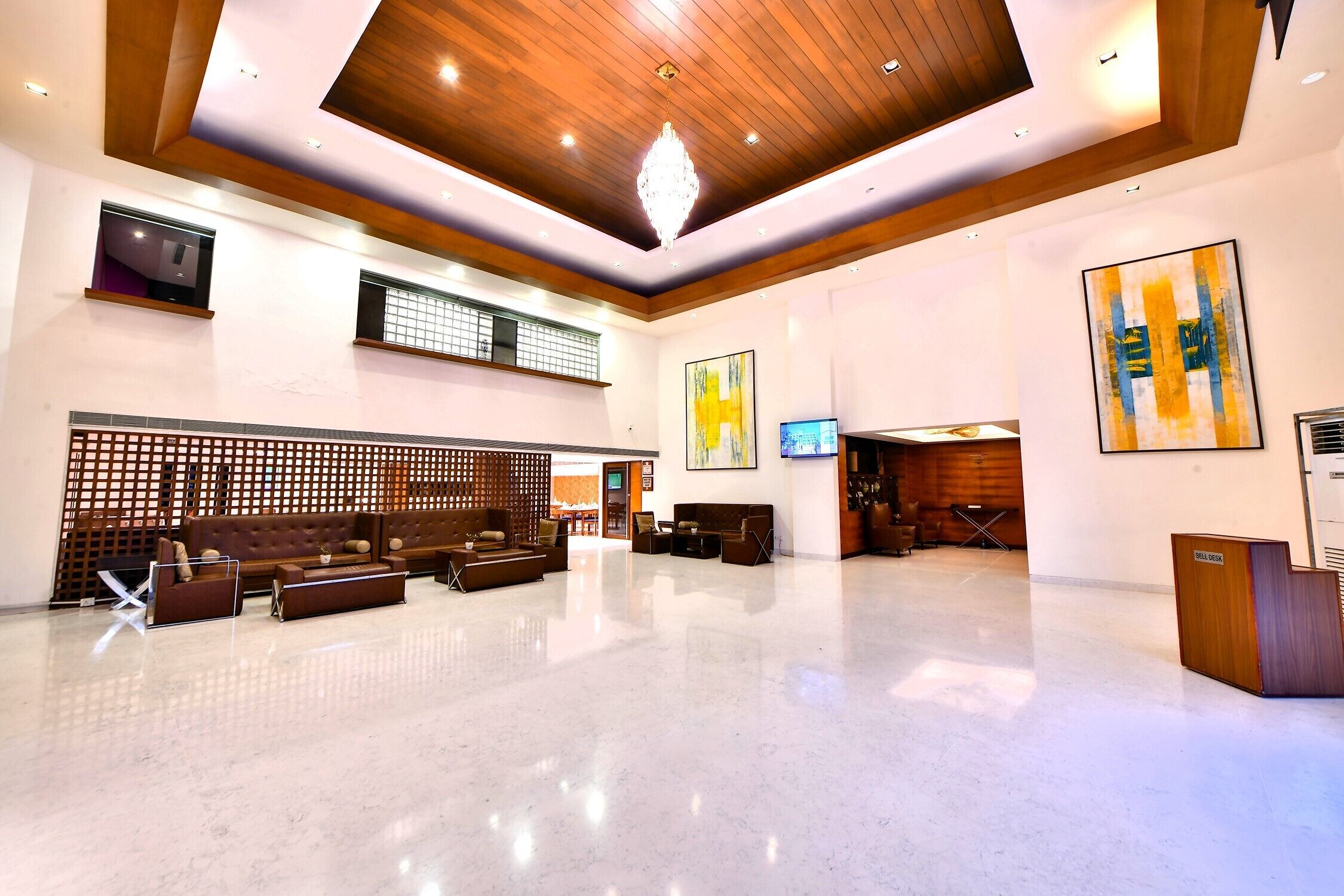 A spacious lobby with a high ceiling, wooden paneling, a reception desk, and seating areas.