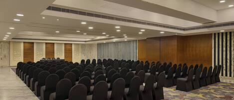 A conference room with rows of chairs, a patterned carpet, and a chandelier.