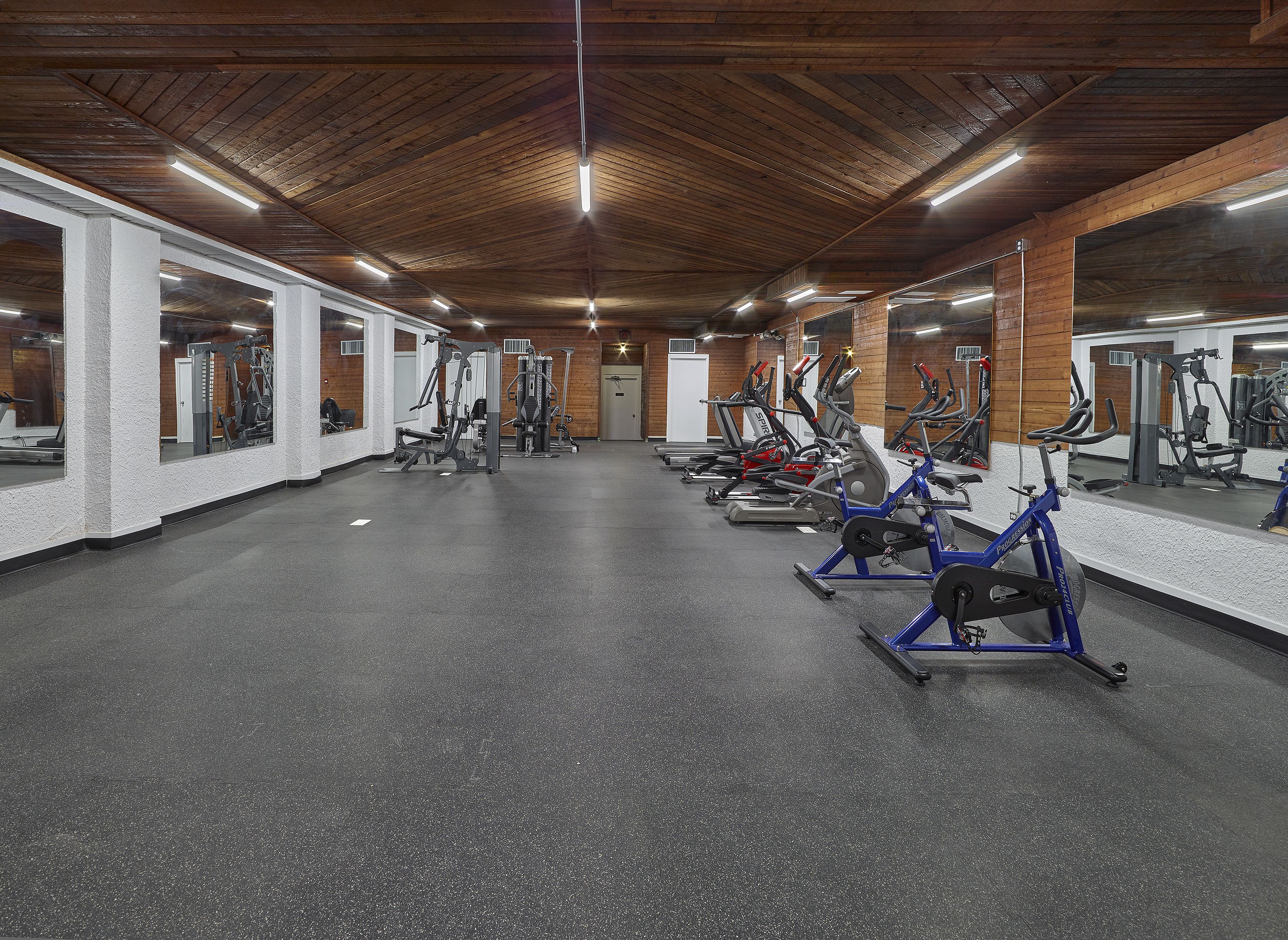 A gym with exercise equipment and mirrors on the walls.