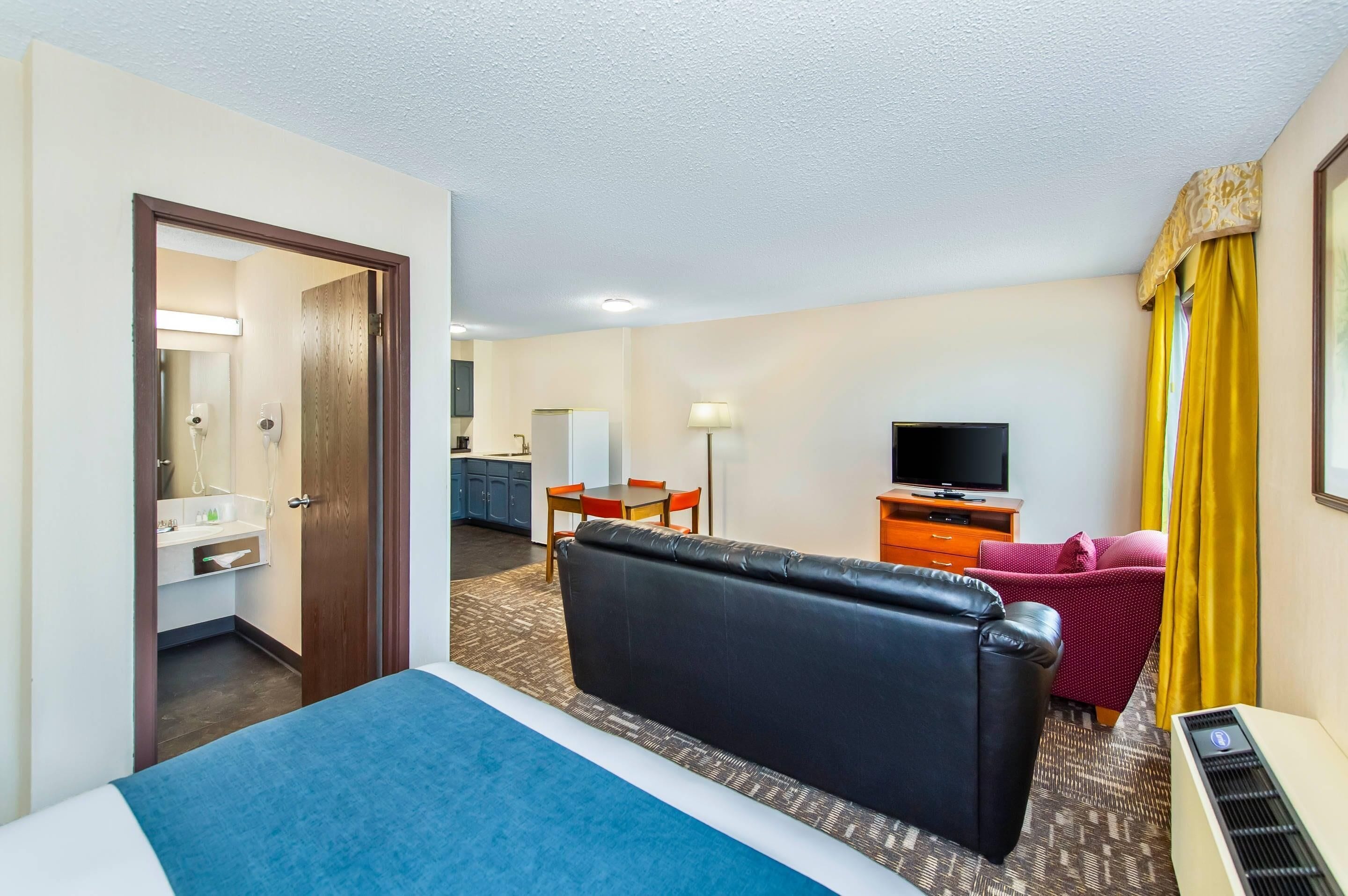 Une chambre d’hôtel avec un lit, un bureau, une télévision et un canapé.