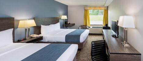 A hotel room with two beds, a desk, a chair, a TV, and a window with curtains.