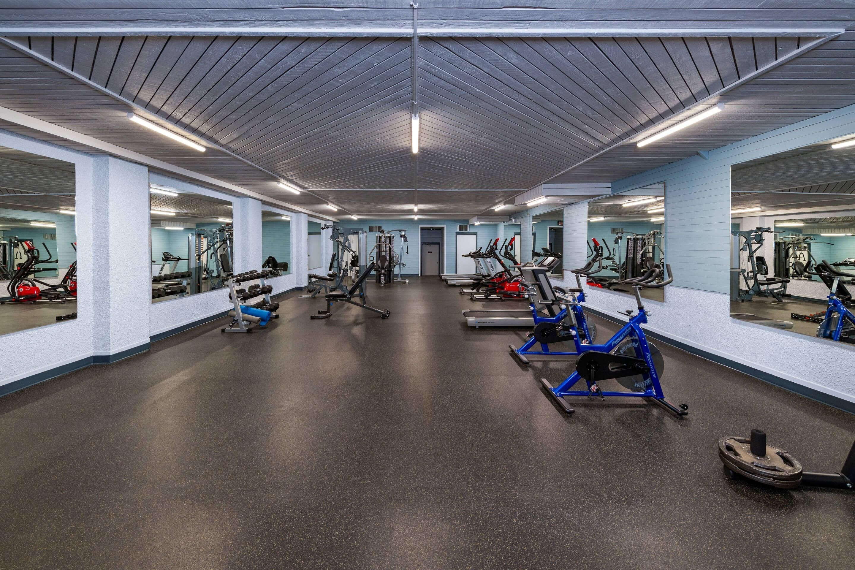 A gym with various exercise equipment, including treadmills, stationary bikes, and weight machines.