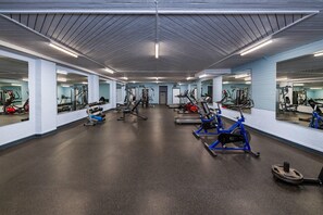 Un gimnasio con varios equipos de ejercicio, incluyendo cintas de correr, bicicletas estáticas y máquinas de pesas.