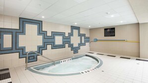 Piscina com design de mosaico em azulejos, uma banheira de hidromassagem e uma placa indicando a faixa de temperatura da piscina.