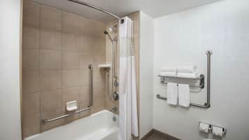 Une salle de bain équipée d’une douche à l’italienne, de barres d’appui, de toilettes et d’un porte-serviettes.