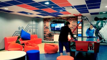 A modern lounge area with colorful seating, a digital screen, and a unique ceiling design.