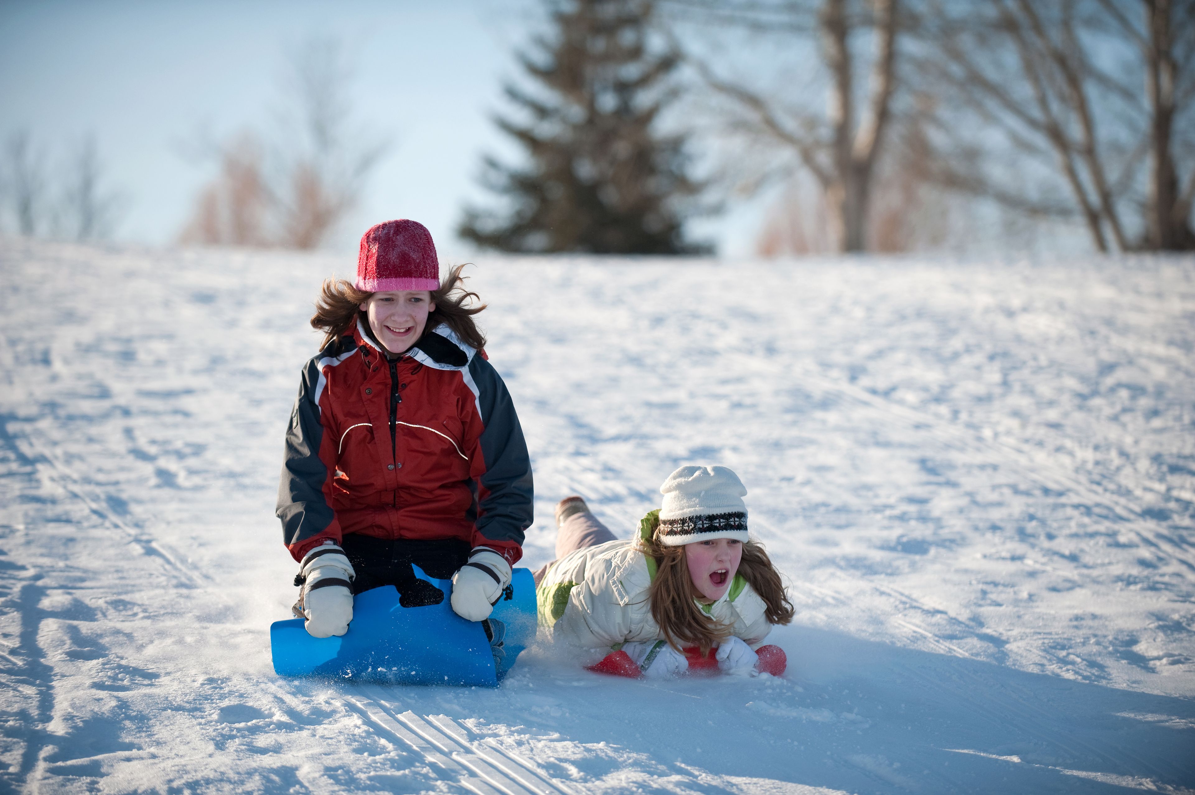 Two people sledding on a snowy slope.