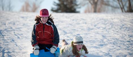 Two people sledding on a snowy slope.