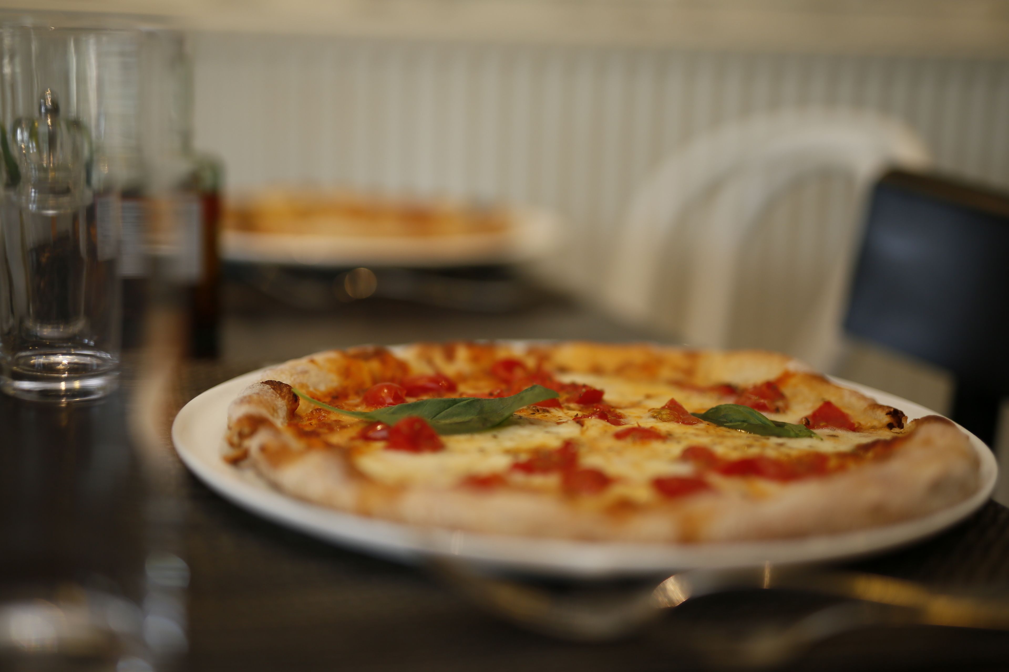 A pizza on a white plate with a blurred background.