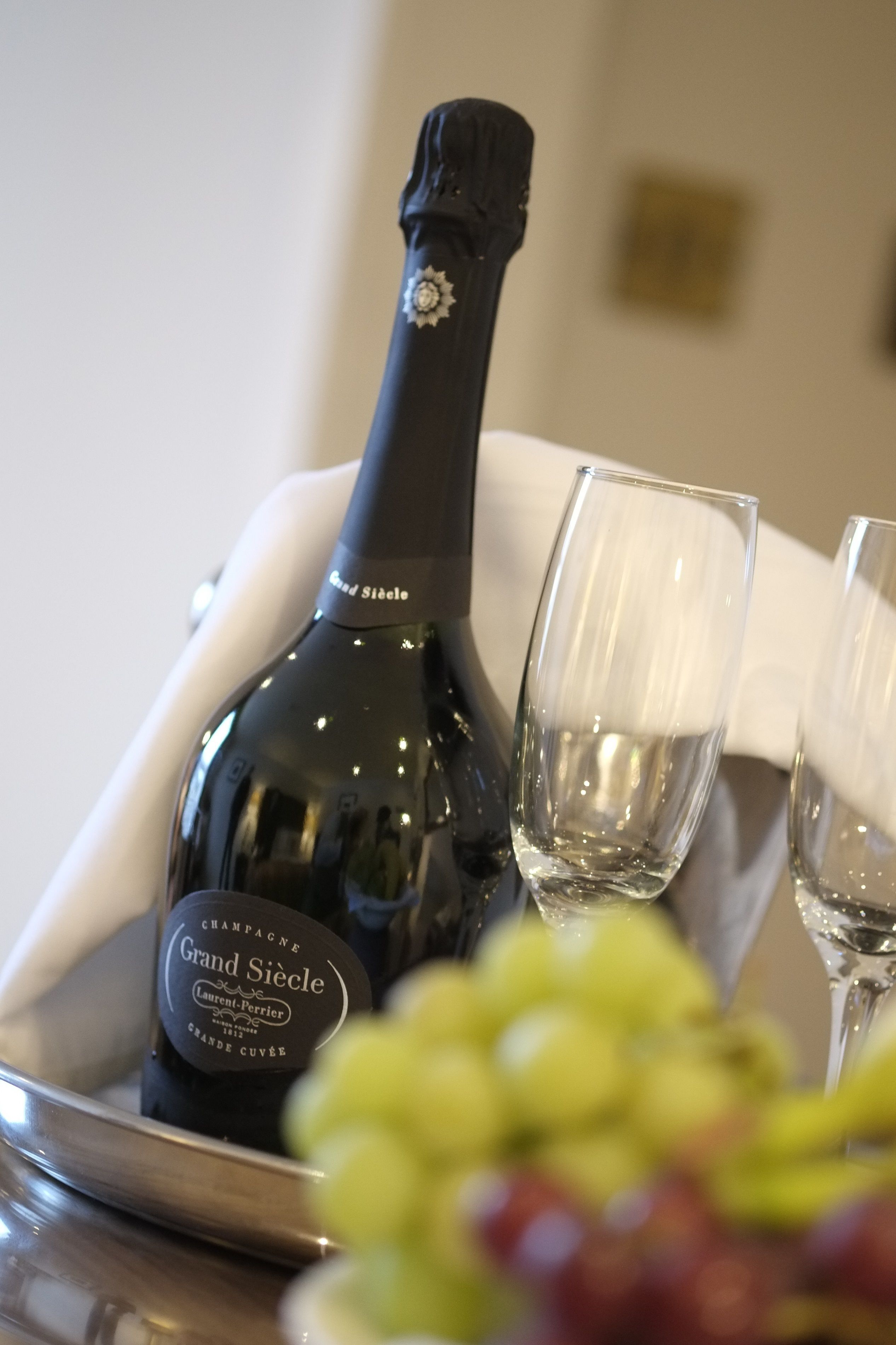 Una botella de champán Grand Siecle, dos copas y una bandeja con uvas.