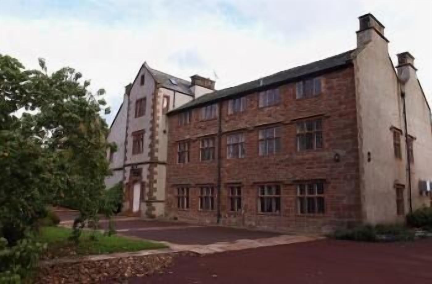 A large, historic building with multiple windows and a prominent chimney.
