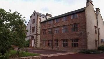 A large, historic building with multiple windows and a prominent chimney.