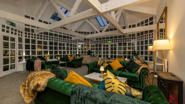 Una habitación amplia con sofás tapizados en verde, una chimenea y un tragaluz.