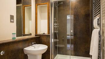 Un baño moderno con ducha de vidrio, un lavabo blanco y dos espejos.
