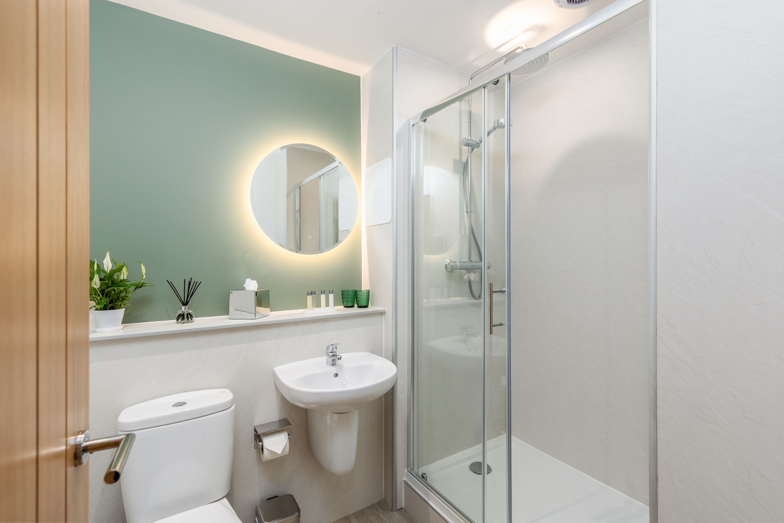 Un baño moderno con inodoro, lavamanos y ducha con mampara de vidrio.