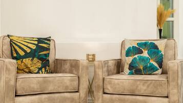 Two armchairs with floral cushions, a small side table, and a vase with dried plants.