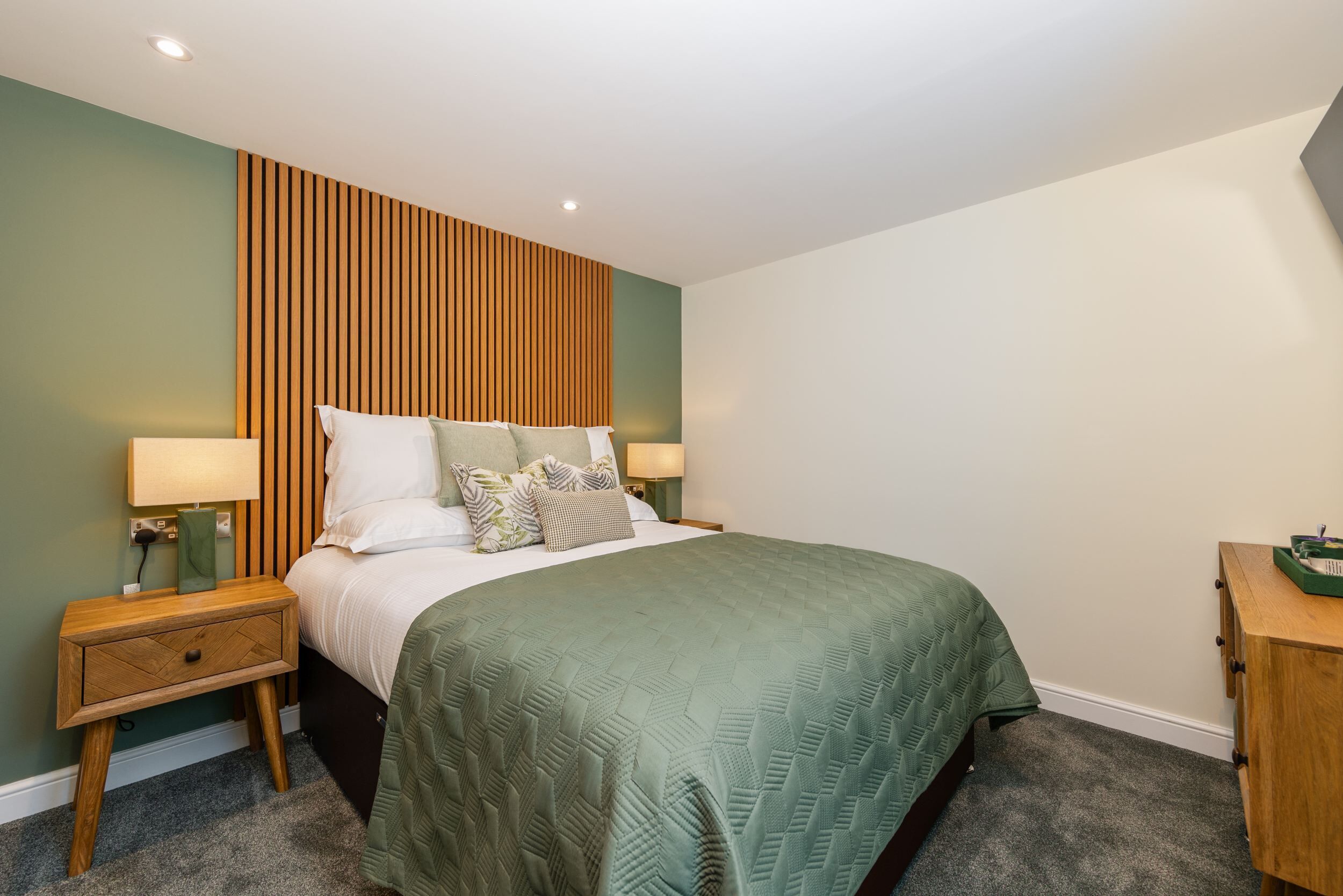 A neatly arranged bedroom with a bed, nightstands, and a dresser.