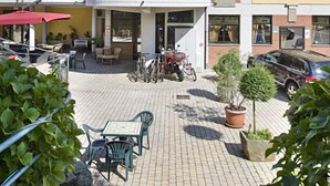 Un patio con mobiliario exterior, un edificio con balcón y cielo despejado.