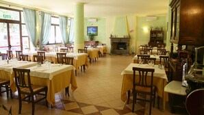 Un restaurante con varias mesas y sillas, una chimenea y un televisor.