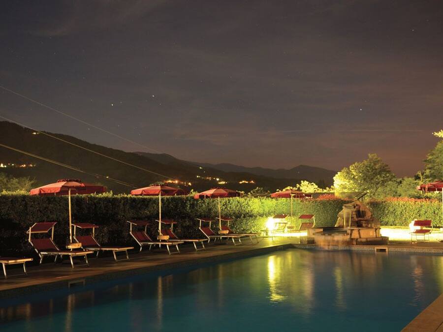 Een buitenzwembad, parasols bij het zwembad en ligstoelen