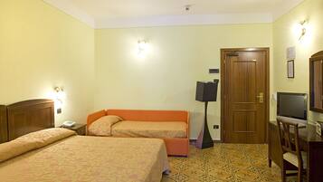A hotel room with two beds, a desk with a television, a door, and a wall-mounted light fixture.