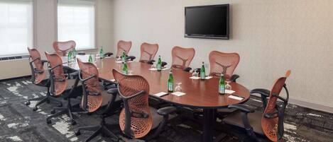 A conference room with a large table, chairs, and a flat-screen TV on the wall.