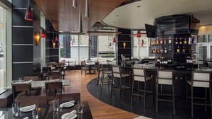 A modern restaurant with a bar area, wooden flooring, and pendant lighting. - DoubleTree Suites by Hilton Hotel Detroit Downtown - Fort Shelby (Detroit)