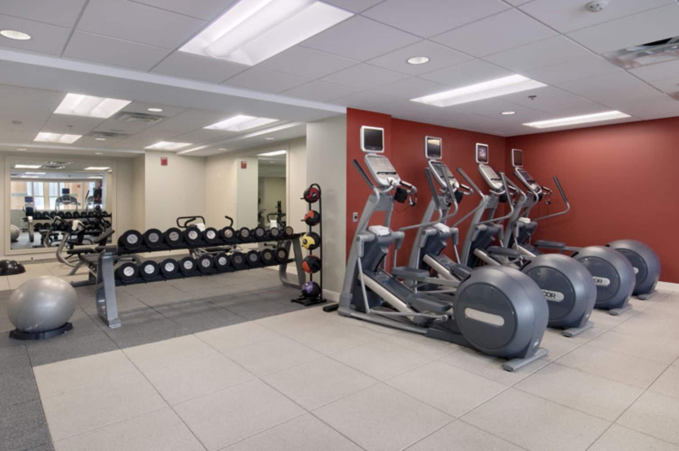 Une salle de sport équipée de tapis de course, d’appareils de musculation et de poids libres.