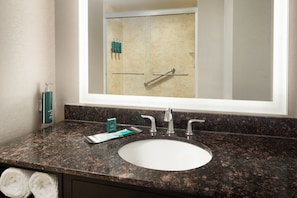 A bathroom with a granite countertop, a white sink, and a large mirror reflecting a shower area. - DoubleTree Suites by Hilton Hotel Detroit Downtown - Fort Shelby (Detroit)