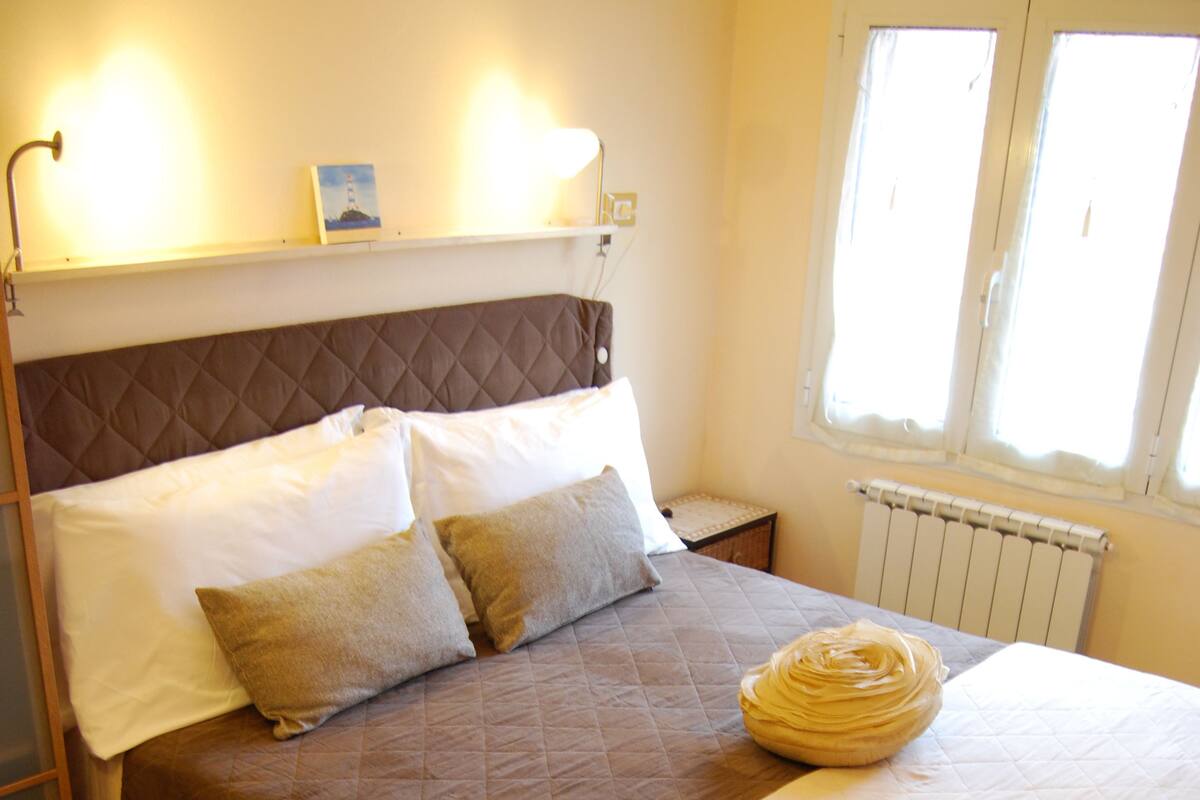 A neatly made bed with a brown quilt, white pillows, and a white comforter.