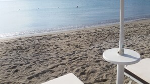 A beach with footprints in the sand, a white umbrella, and a white lounge chair. - B&B Burlamacco Gold (Viareggio)