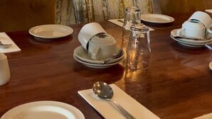 Un comedor con una mesa de madera dispuesta para cuatro personas, incluyendo platos, tazas y cubiertos.