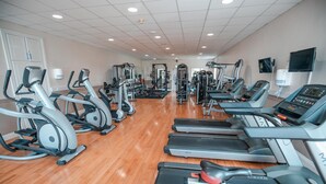 Un gimnasio con numerosas cintas de correr, elípticas y equipo de levantamiento de pesas.